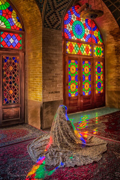 Interior of historic nasir al mulk pink mosque featuring colorful light beams reflecting on carpet from traditional persian stained glass orosi windows in shiraz iran