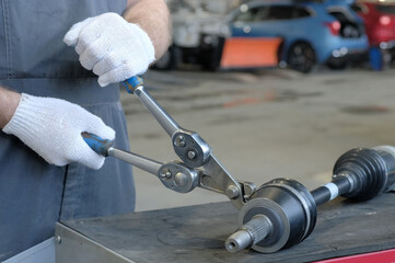 Car repair at a service station. The mechanic attaches the clamp to the dust cover. The drive...