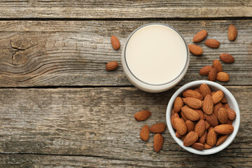 Fresh almond milk in glass and nuts on wooden table, top view. Space for text