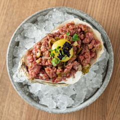 Exquisite Culinary Delight Featuring Fresh Oyster Topped With Finely Diced Beef, Rich Egg Yolk, and Caviar Served on a Bed of Crushed Ice
