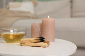 Palo santo sticks, burning candles and tea on white table indoors, space for text
