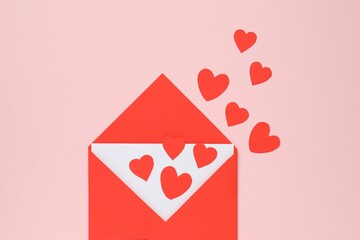 Valentine's Day. Envelope with many paper hearts on pink background, top view