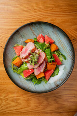 Vibrant Salad With Grilled Duck Breast, Fresh Greens, and Colorful Vegetables Served on a Rustic Wooden Table
