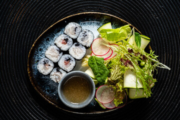 Fresh Sushi Rolls Served Elegantly on a Ceramic Plate Accompanied by a Vibrant Salad and Dipping Sauce, Perfect for a Light and Flavorful Meal Set Against a Textured Background