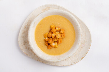 Warm and Inviting Bowl of Creamy Soup Garnished With Crispy Croutons Placed on a Rustic Plate Against a Bright Backdrop
