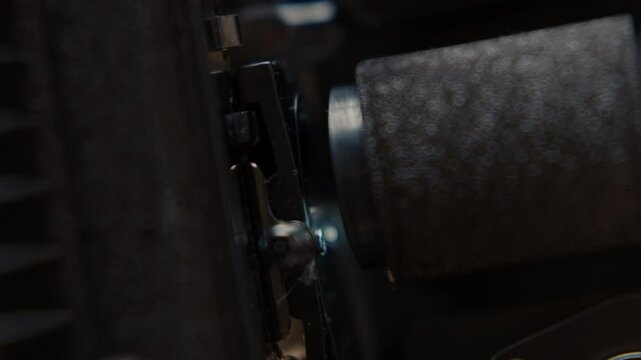 Close ups of a vintage 8MM projector spools moving and playing film 