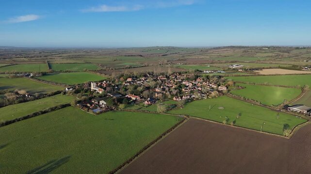 Drone view of Hardwick village surrounded by lush green countryside fields on a sunny day