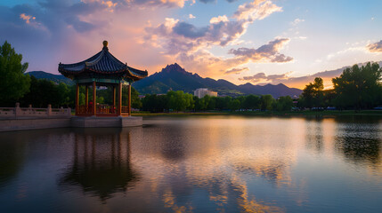 An ancient-style pavilion stands on the calm lake, with mountains in the background and a sunset sky