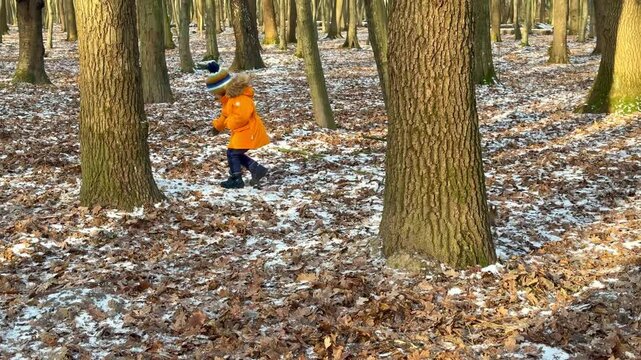 Little boy joyfully plays in snowy park while chasing a curious squirrel