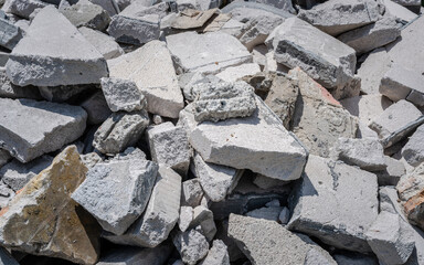 A close-up of a pile of broken concrete rubble. The image shows a variety of shapes and sizes of concrete fragments, with a focus on the rough textures and weathered surfaces.