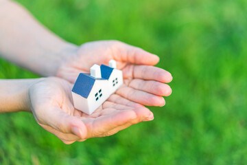 A hand holding two miniature houses, symbolizing homeownership and real estate.