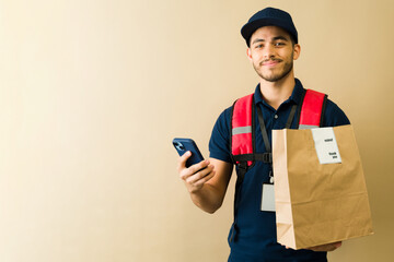 Delivery man using smartphone and holding package