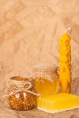 Beekeeping products, honey and pollen. Beeswax candles, handmade honey soap, on a beige background of crumpled paper. copy space