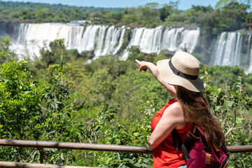 Turista feliz en el Parque Nacional Iguazú, señalando las cataratas y las caídas de agua