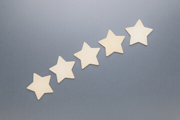Wooden five stars arranged as shooting stars on gray background,  Five-star rating, customer feedback, and evaluation concept.