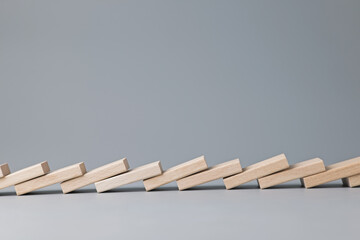 All wooden dominoes in a row fall down, domino effect concept, with copy space