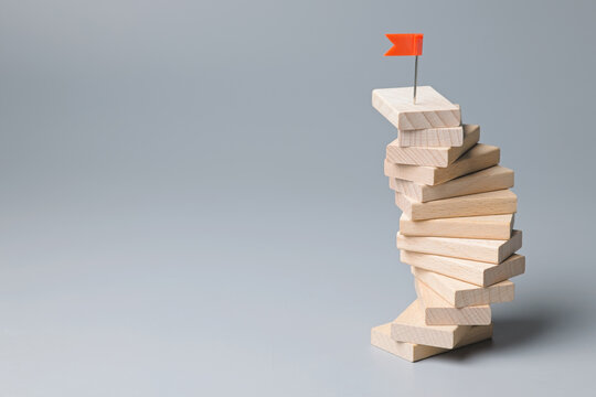 Wooden pieces arranged to a winding wooden staircase to success, an effort that seems to be stuck in place but climbing to the top, goal setting, consistency behaviors concept