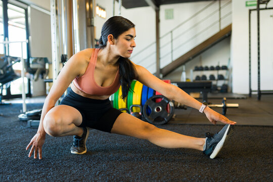 Muscular athlete stretching quadriceps on exercise mat, focusing on muscle recovery and preventing workout-related injuries
