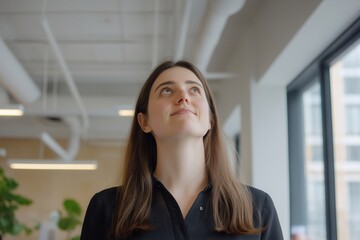 Happy confident young professional woman, female entrepreneur, businesswoman looking away, standing in office at work dreaming of future success.