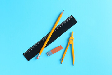Ruler, pencil, eraser and compass on light blue background, flat lay
