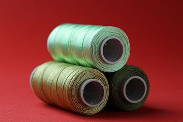Spools of colorful sewing threads on red background, closeup