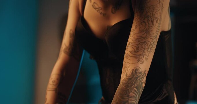 Tattoos on body of beautiful young woman, alternative style of appearance. Close-up view of slender female arms with ink patterns, lady smiling and laughing, rock and punk style of clothing, details