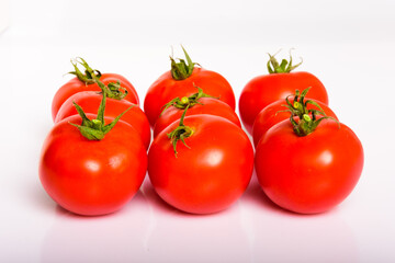 Frische, rote Tomaten mit Stengeln vor weißem Hintergrund isoliert, in der Gruppe