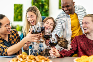 Young multiethnic people with dog drinking and toasting red wine at lunch party - Happy drunk friends having fun together at restaurant winery bar - Food, beverage at dinning life style concept