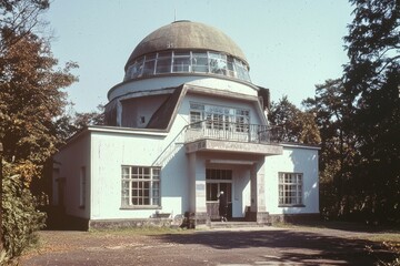 Obraz premium Historic architectural structure featuring a dome, showcasing mid century design and surrounded by lush greenery in a serene environment