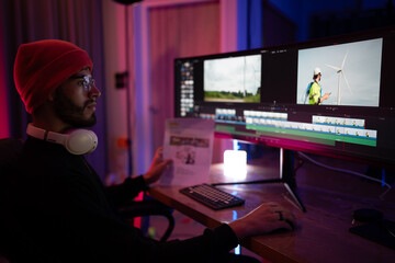Creative video editor working late at night on a dual monitor setup in a dimly lit room
