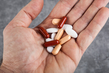 Pills in hand on a grey background. Close-up.