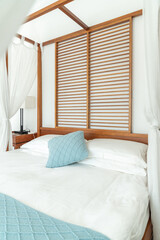 Simple and elegant bedroom with a canopy bed, draped with light white curtains that add a sense of...