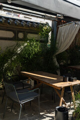 A modern and cozy outdoor dining area, adorned with bamboo and greenery, creating a tranquil and relaxing atmosphere. The furniture features simple wooden and metal designs,