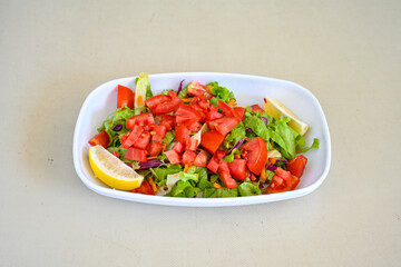 Green salad with arugula, lamb and tomatoes. Healthy vegan dish. Top view at table. Turkish Coban (choban) salata or Shepherds salad, Akdeniz salad in white bowl.