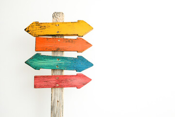 Wooden post with colored directional signs against a white background