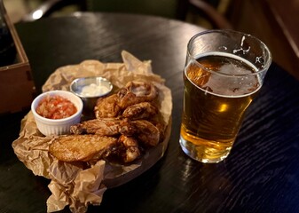 A delicious plate of crispy chicken wings served with a cold refreshing beer, ideal for a laidback night out