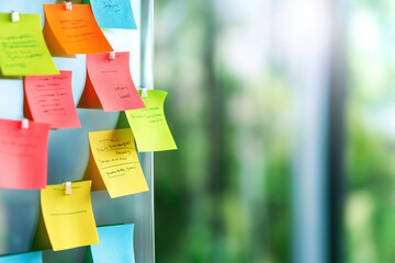 Brightly colored sticky notes on glass board in a vibrant workspace during the day
