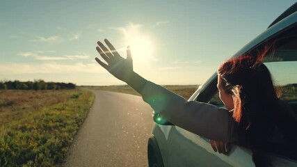 girl rides car with her hand out window, family travel by car, active lifestyle, adventure lifestyle, extending her hand greeting, pulls his face hand out car window, opens window, car countryside