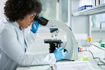 Multiracial  female chemist working on a microscope in laboratory.