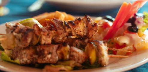 Plate of fish skewers with salad and fries