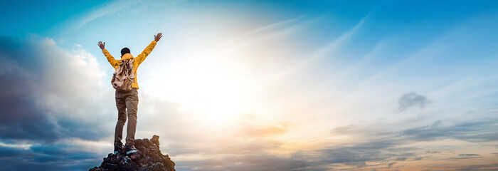 Man traveler on mountain summit enjoying nature view with hands raised over clouds - Sport, travel...
