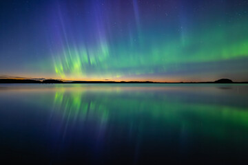 Northern lights dancing over calm lake in north of Sweden. Farnebofjarden national parrk
