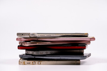 Pile of used smartphones on a plain background depicting electronic waste