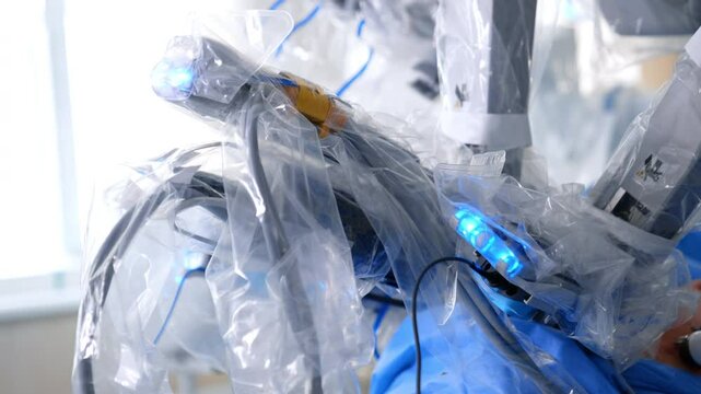 Robotic equipment covered in plastic moves operating the patient. Close up. Laparoscopic surgery in progress.