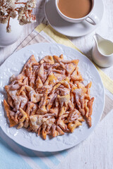 Traditional Maslenitsa dessert angel wings served with coffee on a light background.