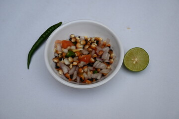 Grilled corn Chaat. Indian style corn salad that's sweet, spicy and tangy. It is mixed with chaat masala, roasted cumin powder, red chili powder, coriander leaves, onion and tomatoes. Indian snacks.