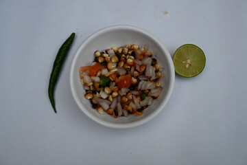 Grilled corn Chaat. Indian style corn salad that's sweet, spicy and tangy. It is mixed with chaat masala, roasted cumin powder, red chili powder, coriander leaves, onion and tomatoes. Indian snacks.