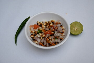 Grilled corn Chaat. Indian style corn salad that's sweet, spicy and tangy. It is mixed with chaat masala, roasted cumin powder, red chili powder, coriander leaves, onion and tomatoes. Indian snacks.