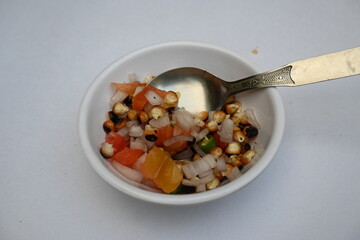 Grilled corn Chaat. Indian style corn salad that's sweet, spicy and tangy. It is mixed with chaat masala, roasted cumin powder, red chili powder, coriander leaves, onion and tomatoes. Indian snacks.