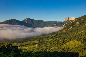 The famous “Trois Becs” Rochecourbe, le Signal and le Veyou, from Vercheny, Drôme, France.  Summer morning with fog in the Drôme valley. Clairette de Die vineyard in the Drôme valley..